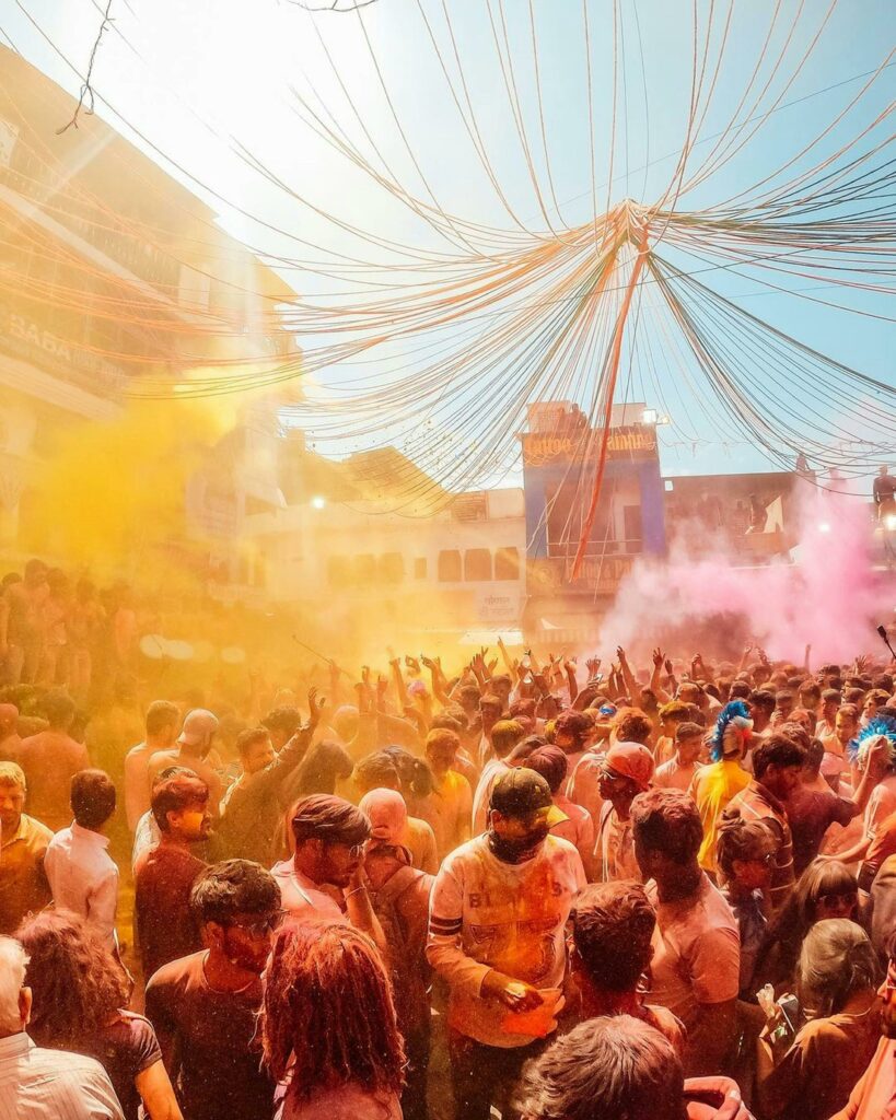 Vibrant Holi festival with a crowd covered in colorful powders, celebrating outdoors.